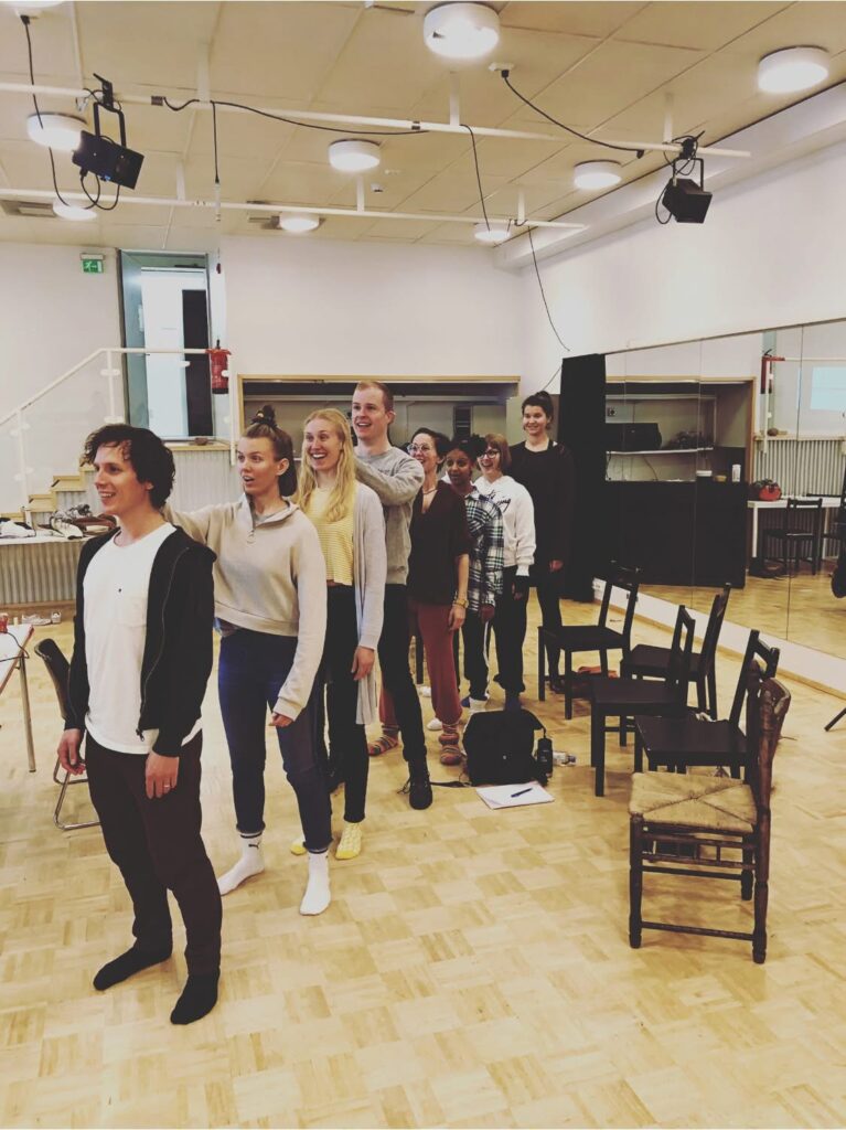 Tapahtumakuva tilanteesta, jossa Vaasan kaupunginteatterin näyttelijät ovat jonossa ja opiskelevat instrumenttitaitoja Antti Annolan johdolla